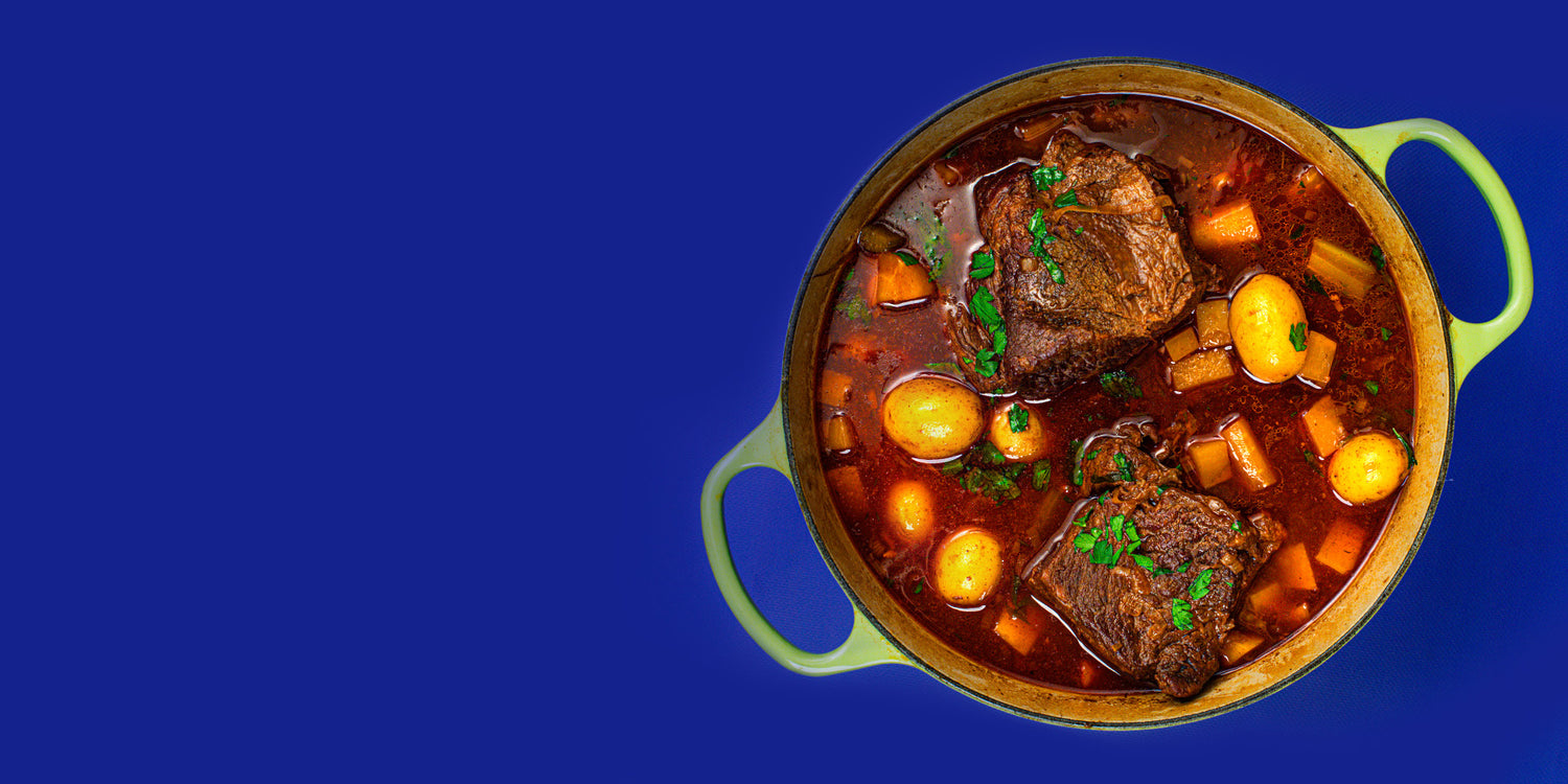 An overhead view of a traditional beef stew with potatoes and carrots in a dutch oven.