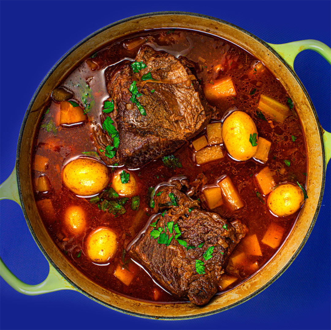 An overhead view of a traditional beef stew with potatoes and carrots in a dutch oven.